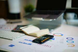 Calculator, notebook and financial reports on a desk.