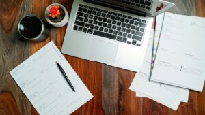 A laptop and planning documents on a wooden desk