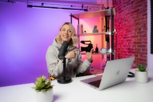 Creator at a desk with a microphone, laptop and video camera in a lit studio.