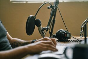 Creator working at a laptop beside a microphone and headphones.