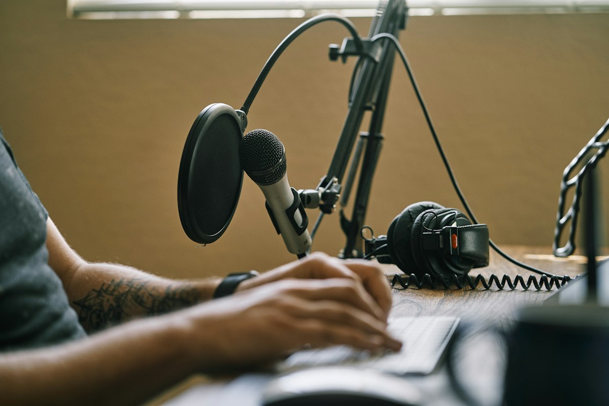 Creator working at a laptop beside a microphone and headphones.
