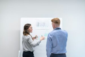 Two engineers discussing a project at a whiteboard